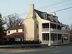 Two-and-one-half-story building on corner of road intersection. Facade fronts the larger road.