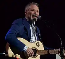 Country musician John Berry singing while playing a guitar