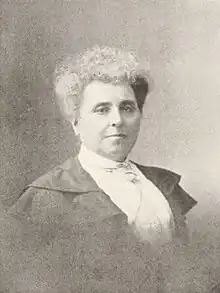 B&W portrait photo of a woman with her white hair in an up-do, wearing a white blouse and dark jacket.