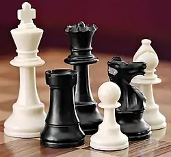 A selection of black and white chess pieces on a checkered surface.